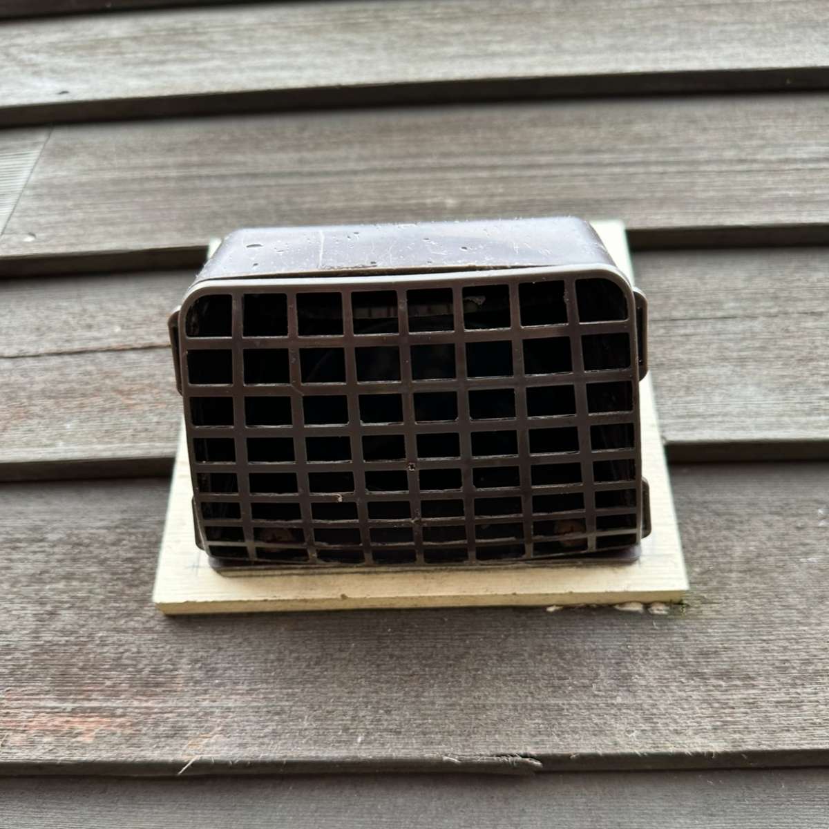 Dryer vent exhaust cover on wooden surface, illustrating the importance of proper ventilation for fire prevention and indoor air quality.