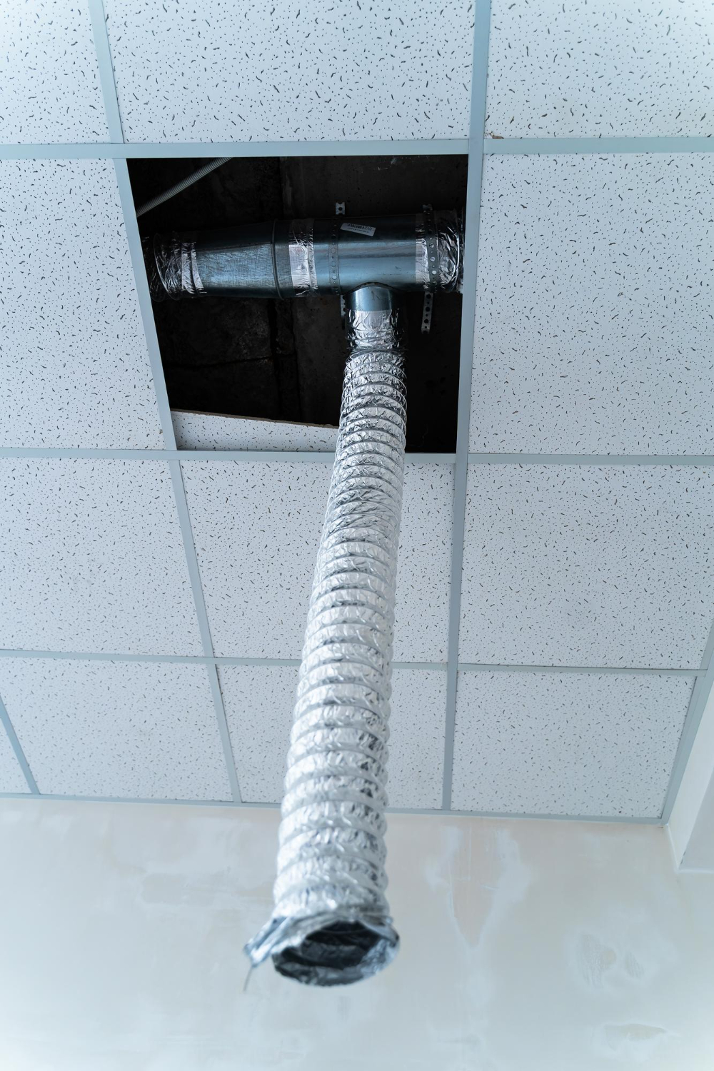 Ductwork and dryer vent visible through ceiling tiles, showcasing professional air duct cleaning service by Kealey's Duct and Dryer Cleaning.