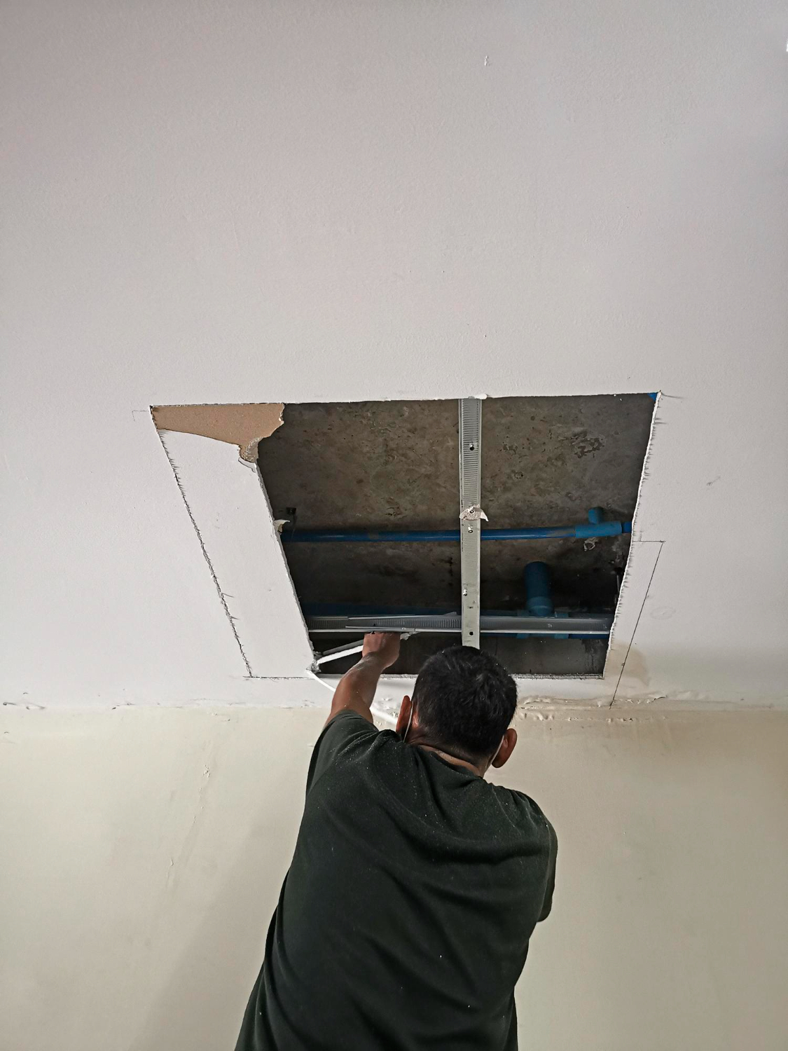 Man reaching into an open ceiling access panel for duct cleaning, showcasing the thorough process of air duct maintenance.