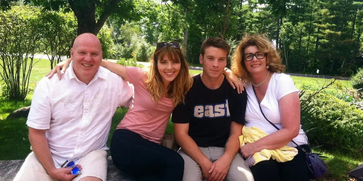 Family photo featuring four smiling individuals outdoors in a lush green setting, emphasizing community and connection, relevant to Kealey's Duct and Dryer Cleaning Service's family-oriented approach.