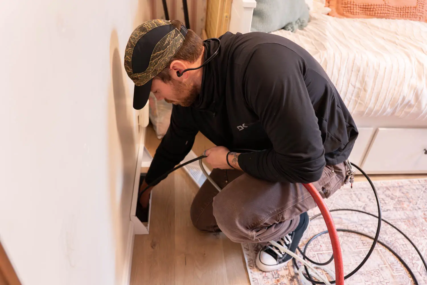 Technician using specialized equipment to clean air ducts in a home, demonstrating professional HVAC cleaning services for improved air quality and system efficiency.