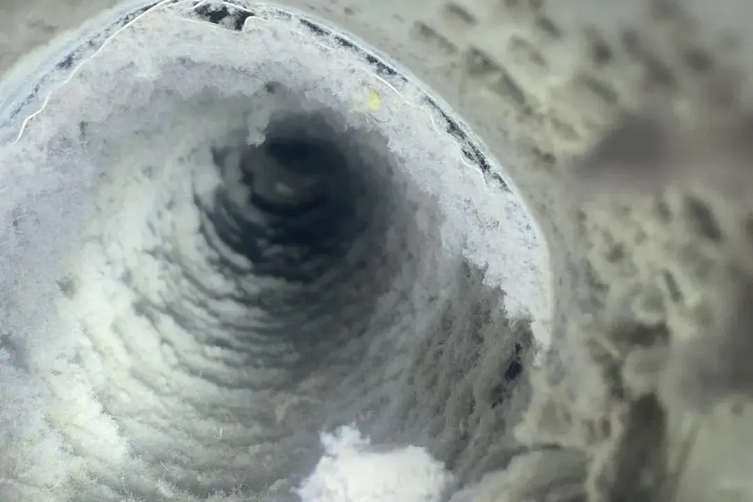 Close-up view of a dirty air duct filled with dust and lint, illustrating the need for regular air duct cleaning to improve indoor air quality and HVAC efficiency.
