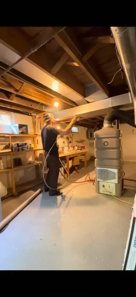 Professional technician cleaning air ducts in a basement, using specialized equipment for HVAC maintenance and indoor air quality improvement.