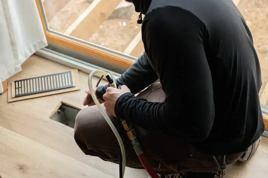 Technician cleaning air duct vent during new home move-in, ensuring clean airflow and safety.